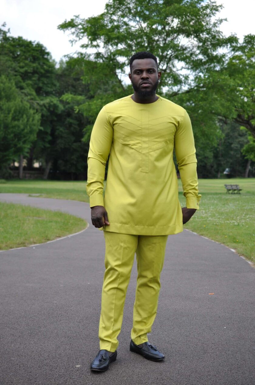 Full frontal of model wearing a custom made solid chartreuse yellow African men's suit with embroidery detail on chest in matching colour.