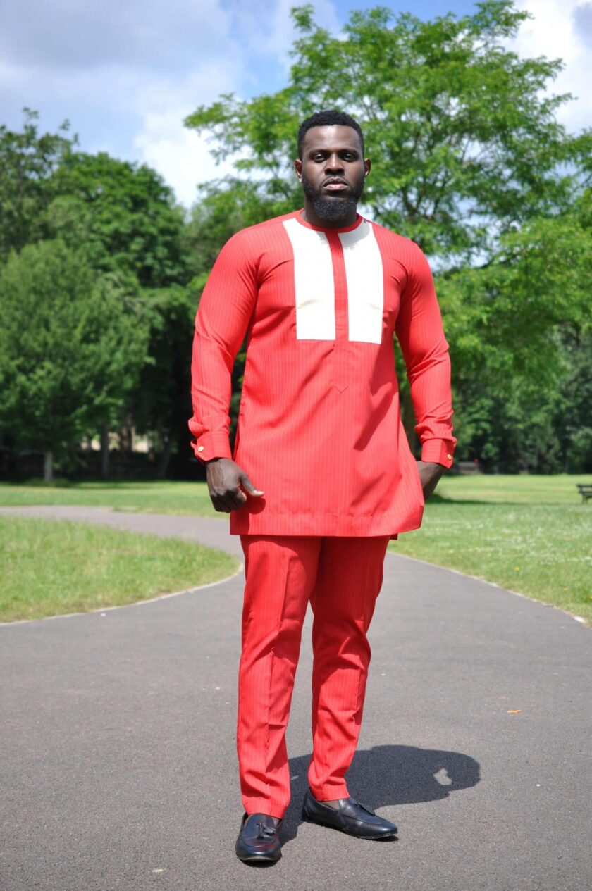 Full frontal of model wearing a custom made solid red men's African suit with two white vertical embroidery panels on the chest.