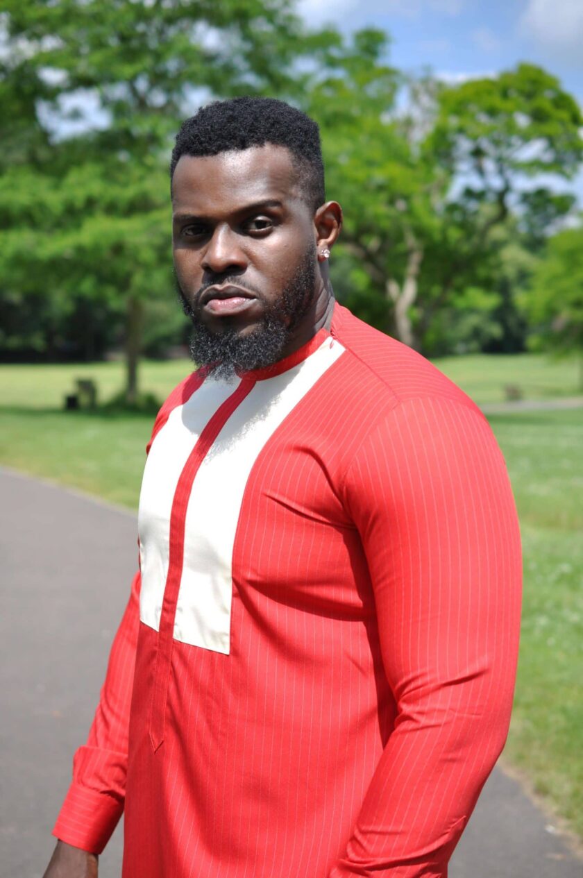 Close side shot of model wearing a custom made red African suit top with white embroidery on the chest.