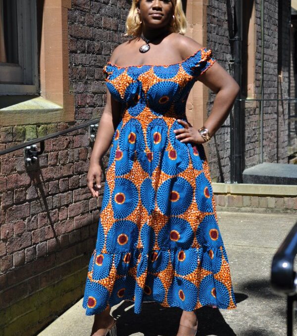 Full frontal of model wearing a blue cap sleeve maxi dress in all over subra African print.