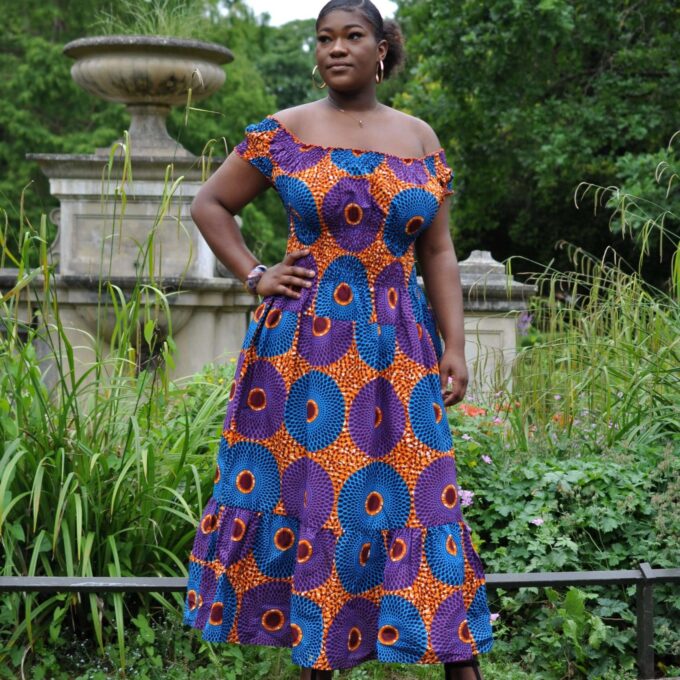 Full frontal of model wearing a colourful ruffle hem cap sleeve maxi dress in all-over African circle print.