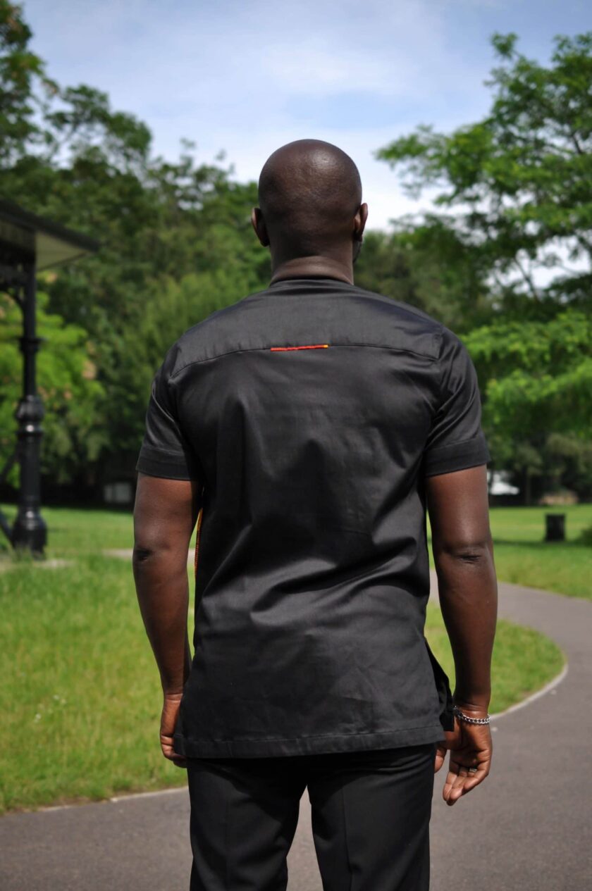 Back shot of model showing the solid black back to to this men's African Kente print shirt.