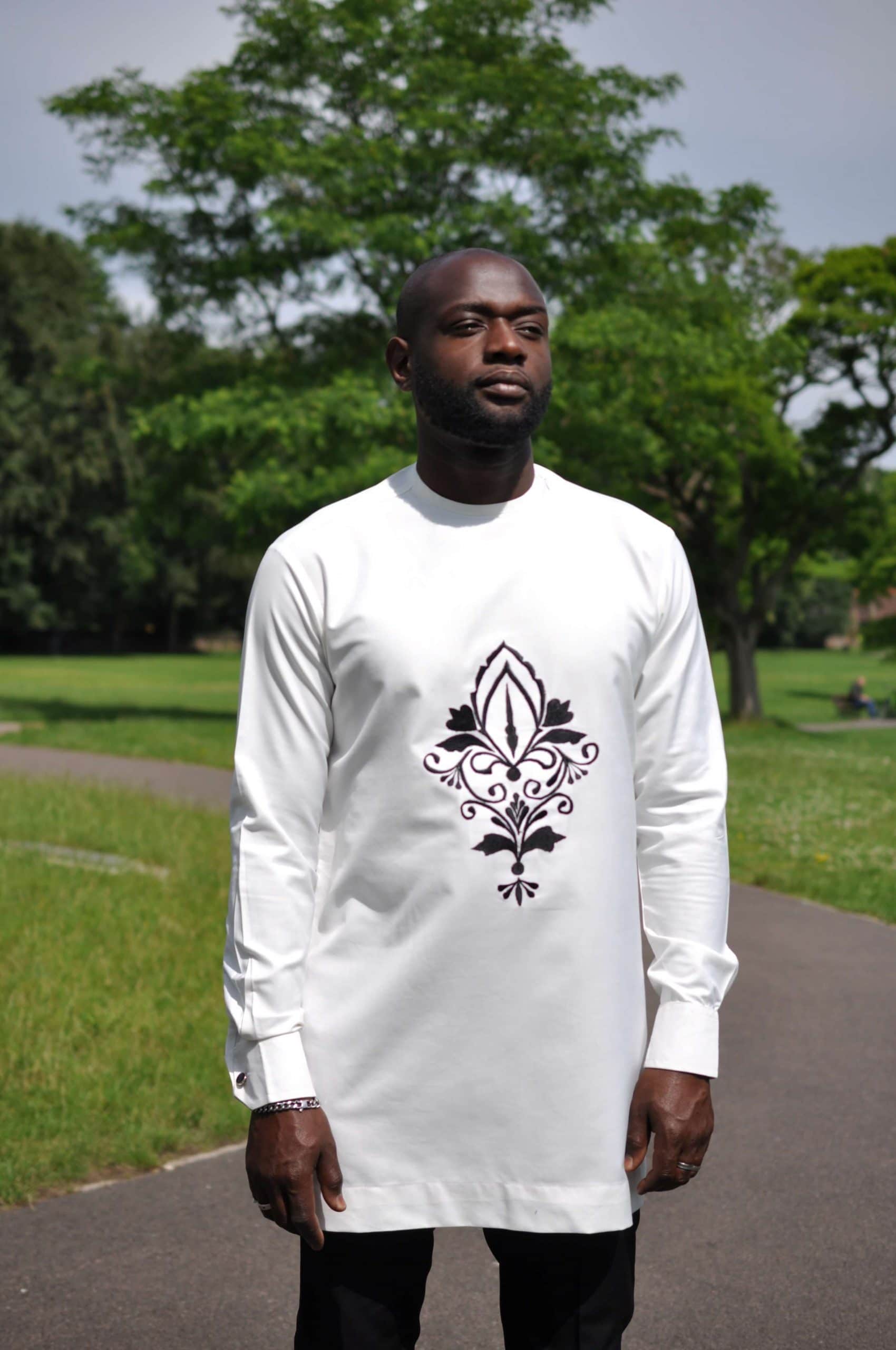 Close front shot of model wearing a solid cream men's African suit top with a printed flower image on the chest.