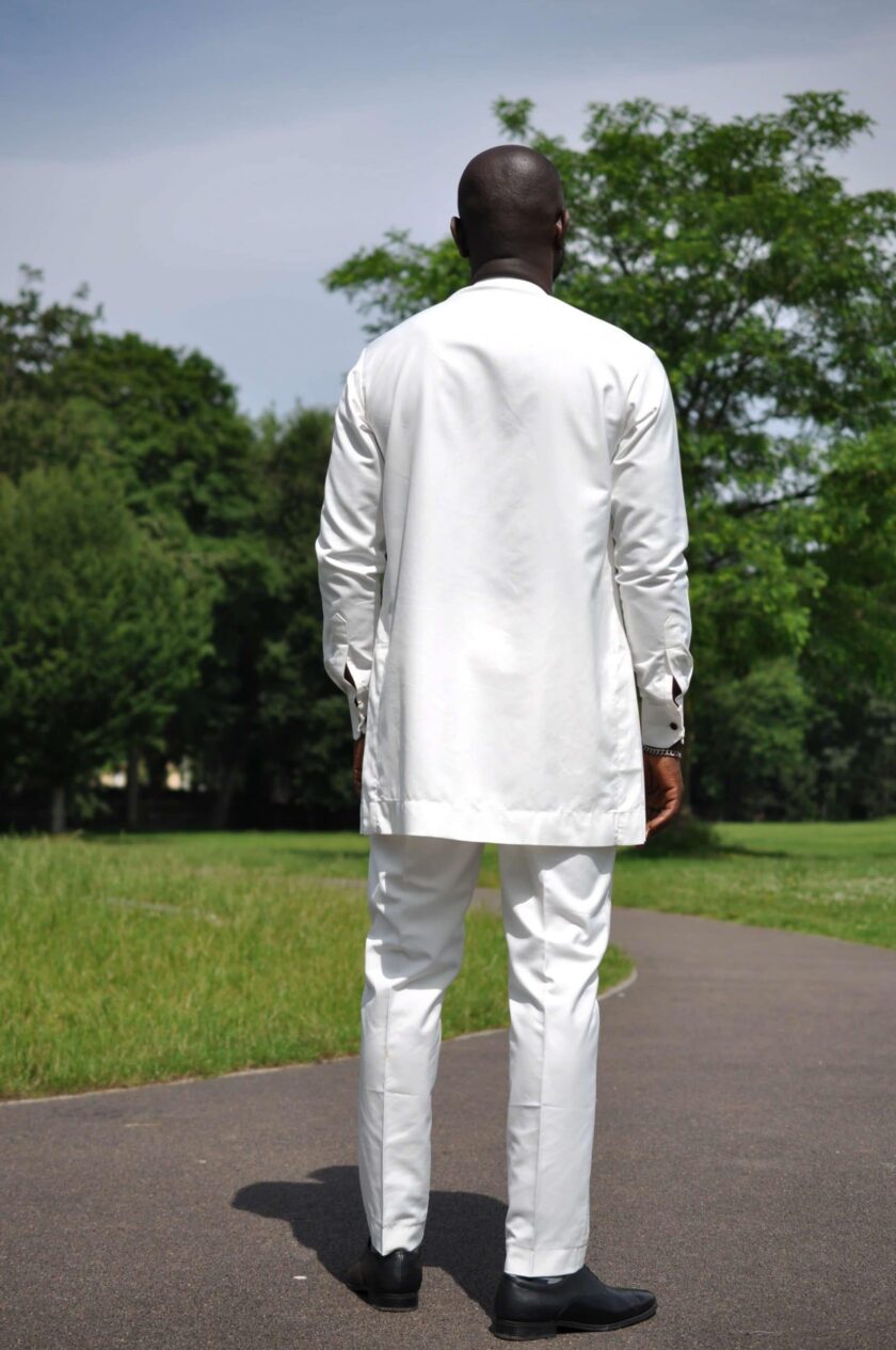 Full back shot of model wearing a solid cream men's African suit.