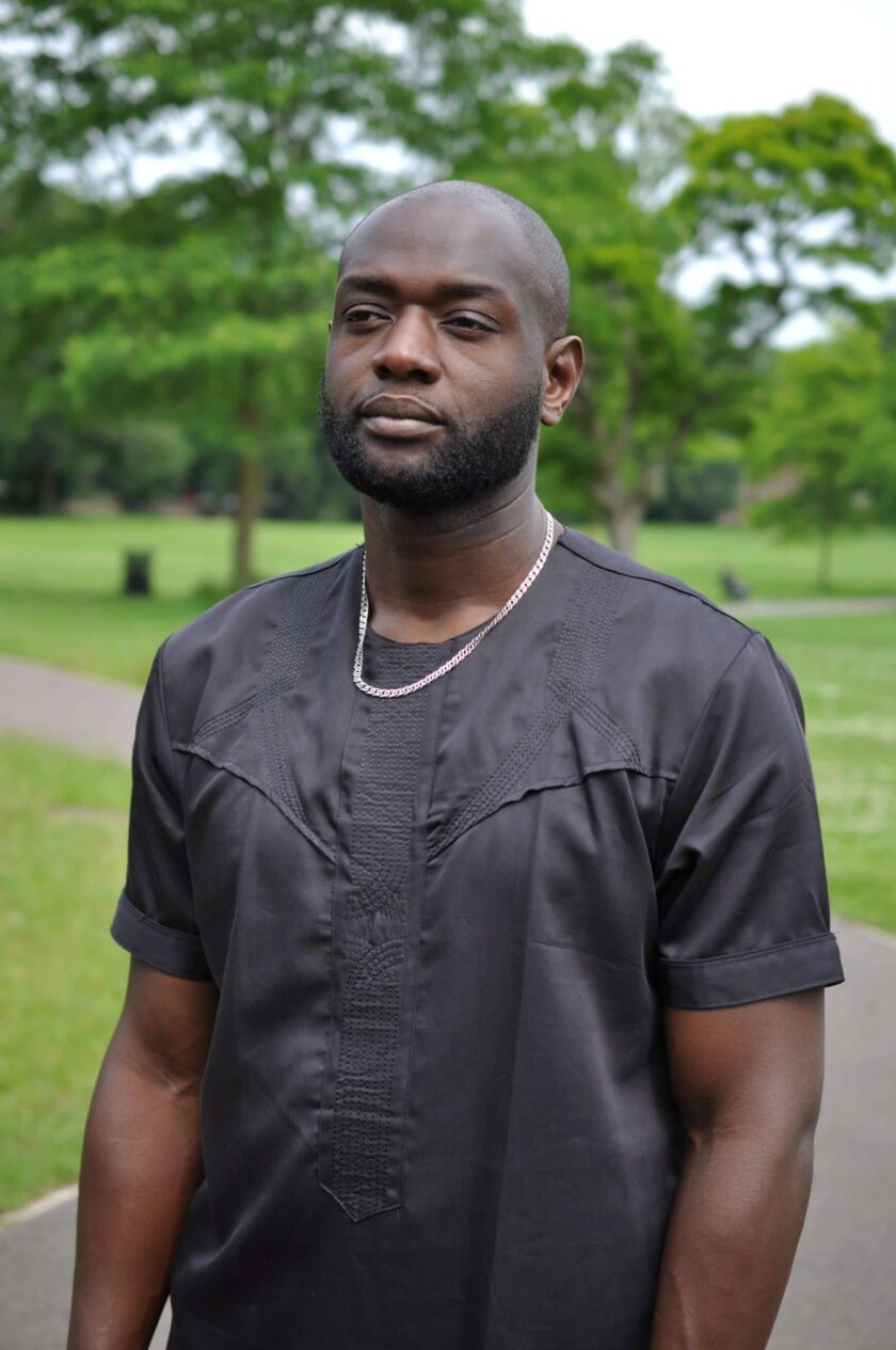 Close frontal of model wearing our men's African shirt showing the simple black embroidery design with symmetrical diagonal lines and a central vertical strip from neckline to waist.