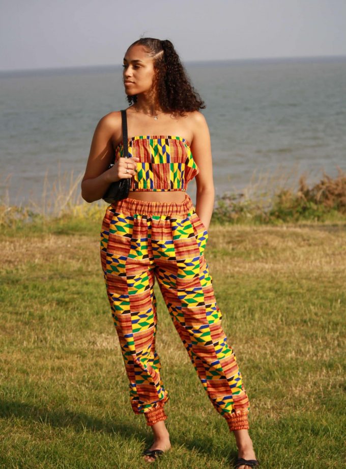 Full frontal of model wearing a bandeau crop top and matching joggers in colourful African print.