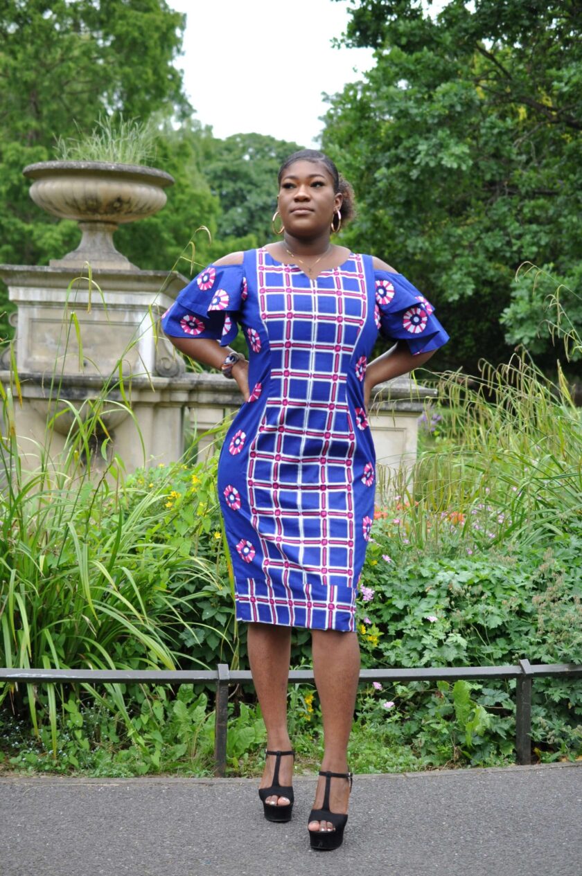 Full frontal of model wearing a blue custom made African midi dress with a mixed geometric African print pattern.