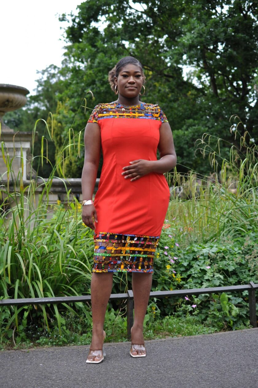 Full frontal of model wearing a solid indigo red bodycon dress with mesh detail on the neckline and hem in multi-coloured African print.