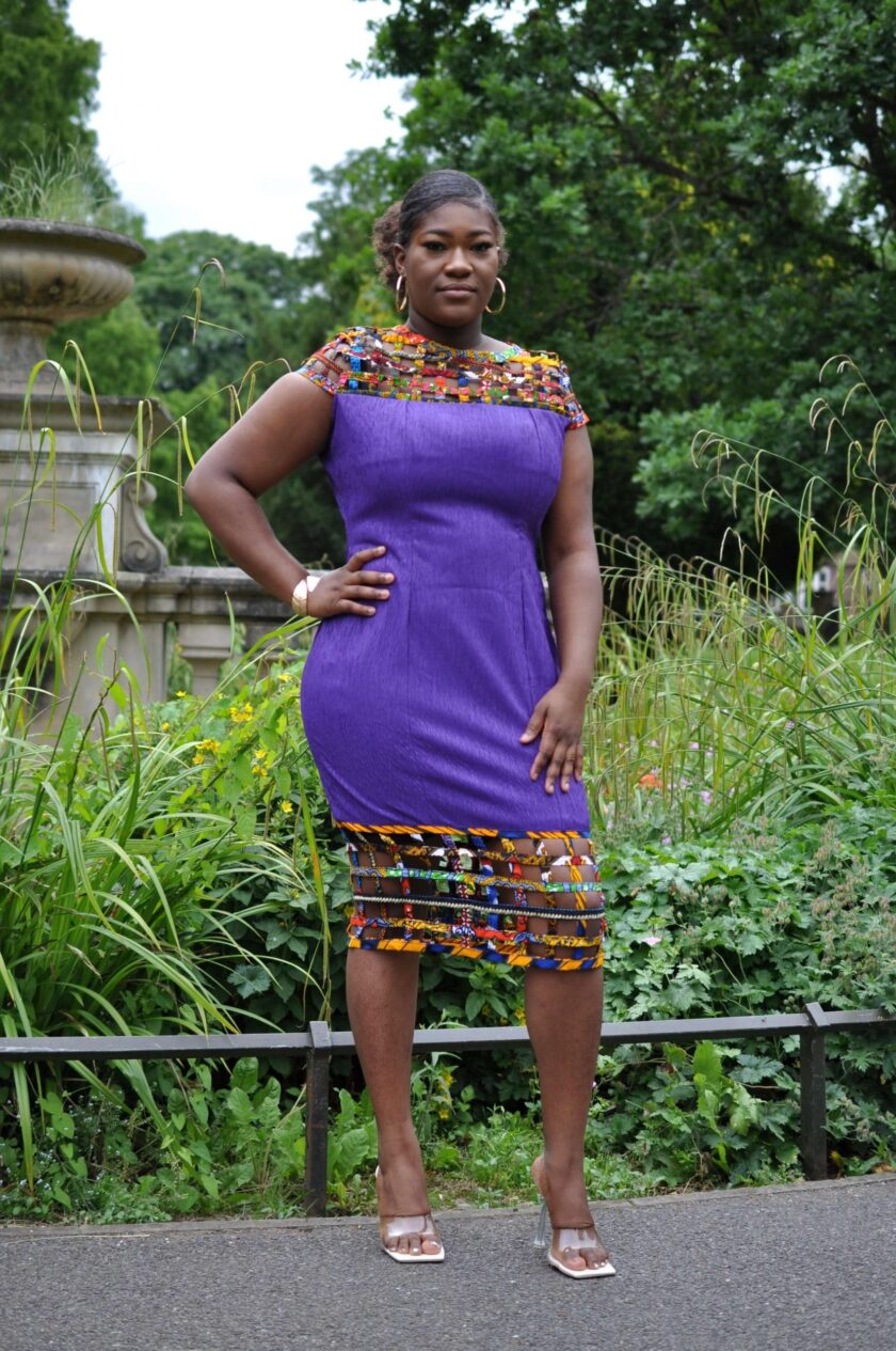 Full frontal of model wearing a solid indigo purple bodycon dress with mesh detail on the neckline and hem in multi-coloured African print.