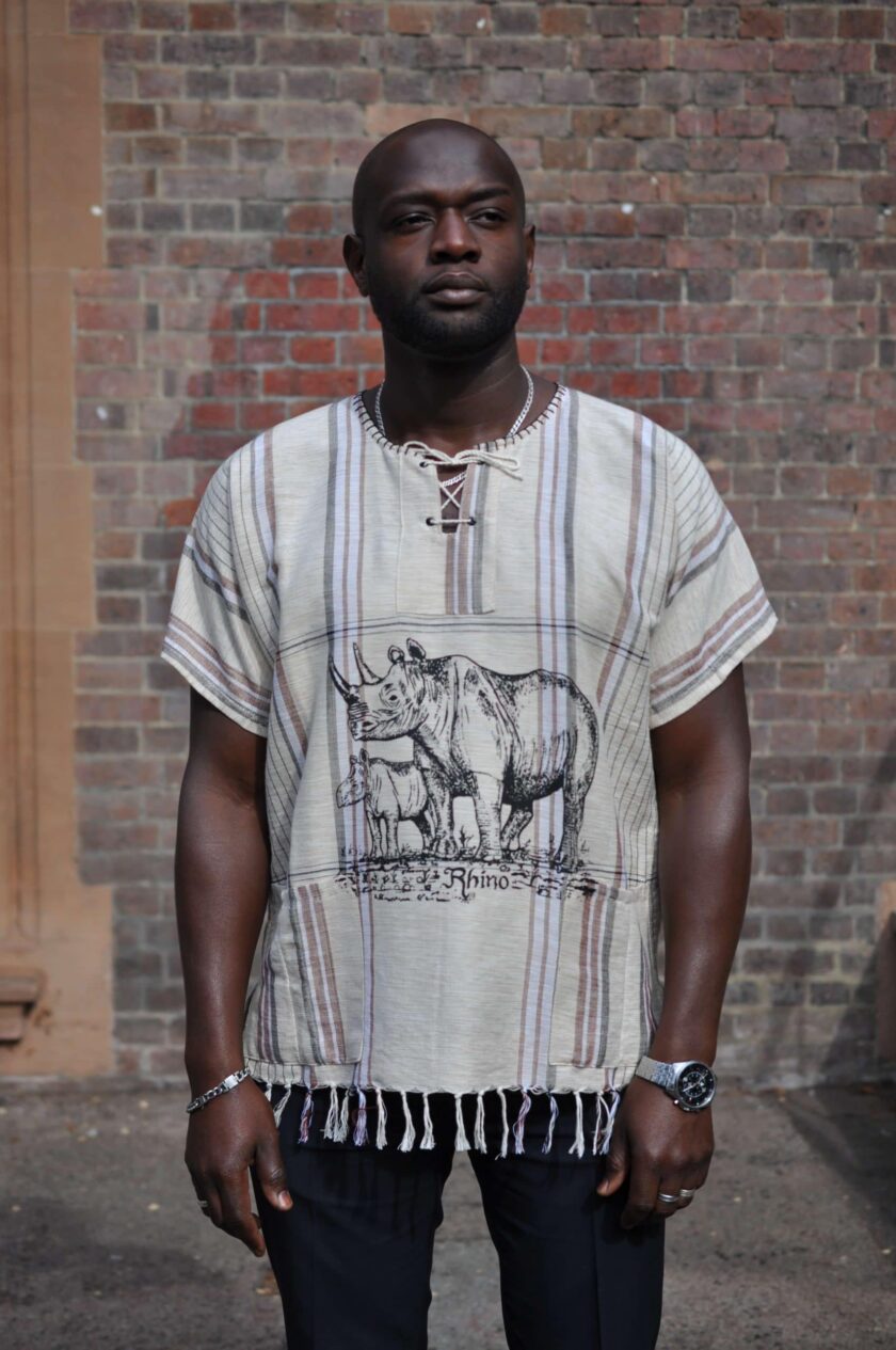 Frontal of model wearing a short sleeved beige boho shirt with African Rhino scene (adult and baby) on the front.