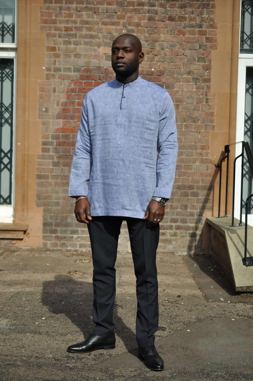 Frontal of model wearing a light grey men's long sleeve polo shirt made from linen. Features black overcast stitching on collar, opening and cuffs.