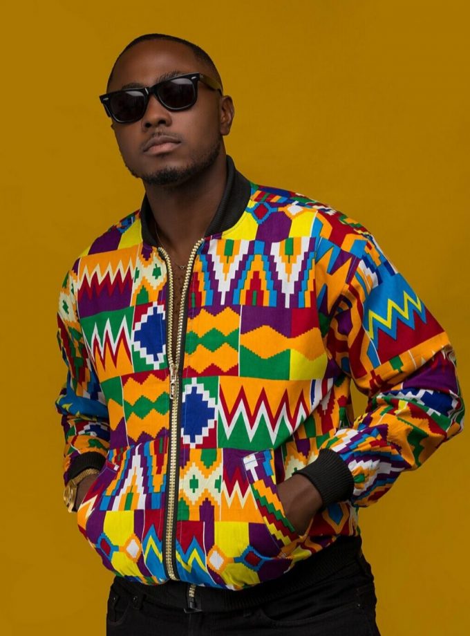 Frontal of model wearing an African inspired unisex bomber jacket in all over vibrant multi-coloured African Kente print.