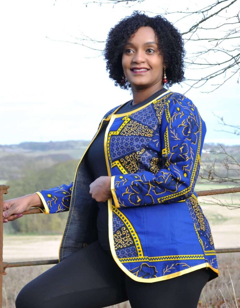 Frontal of model wearing a ladies blue and gold open front jacket in all over African Akufo print.