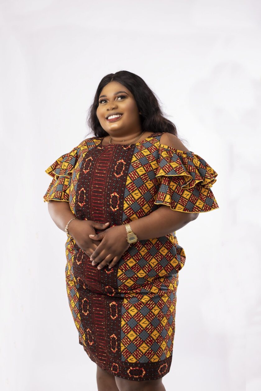 Frontal of model wearing a plus size cold shoulder frill dress in all over African print.