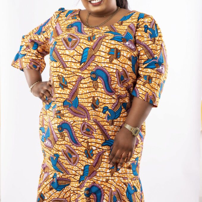 Frontal of model wearing a plus size high low flared midi dress in gold and blue all over African Ankara print.