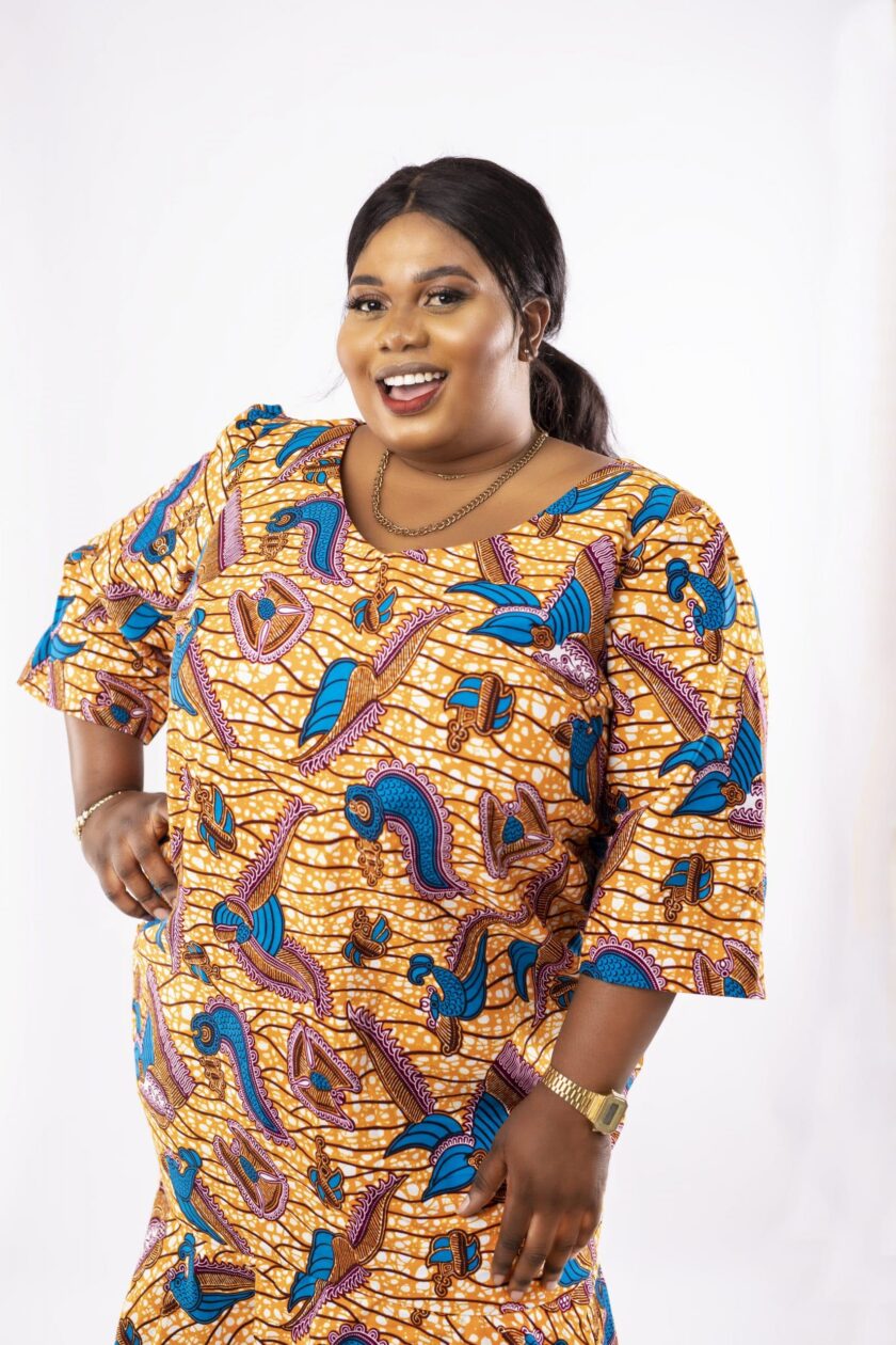 Frontal of model wearing a plus size high low flared midi dress in gold and blue all over African Ankara print.