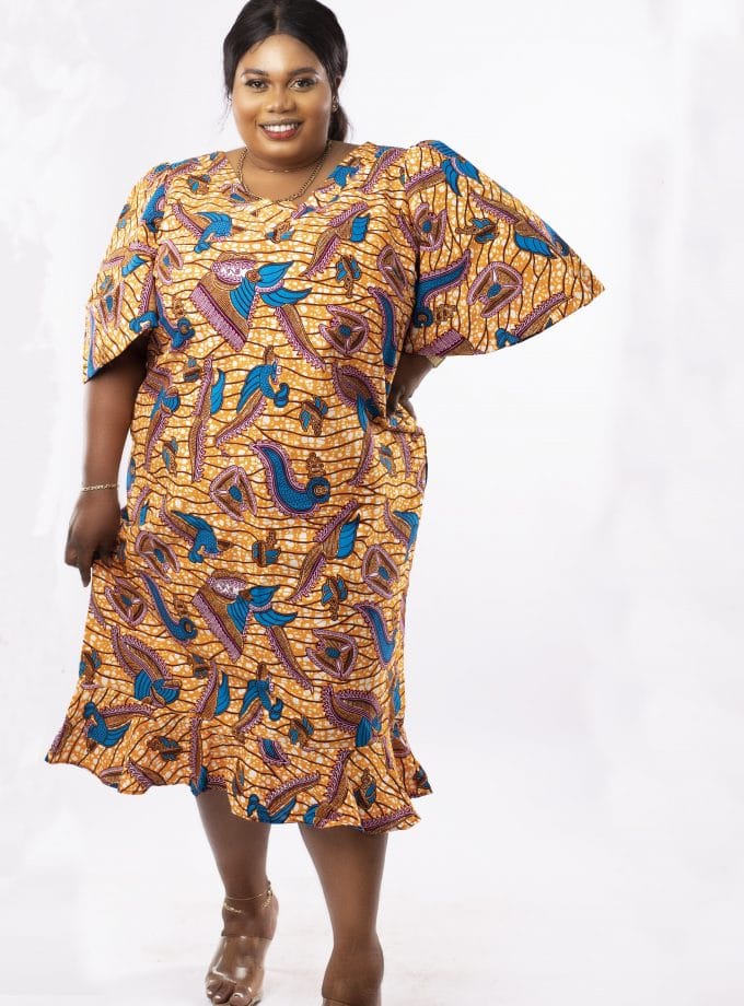 Frontal of model wearing a plus size gold and blue midi dress in all over African print.