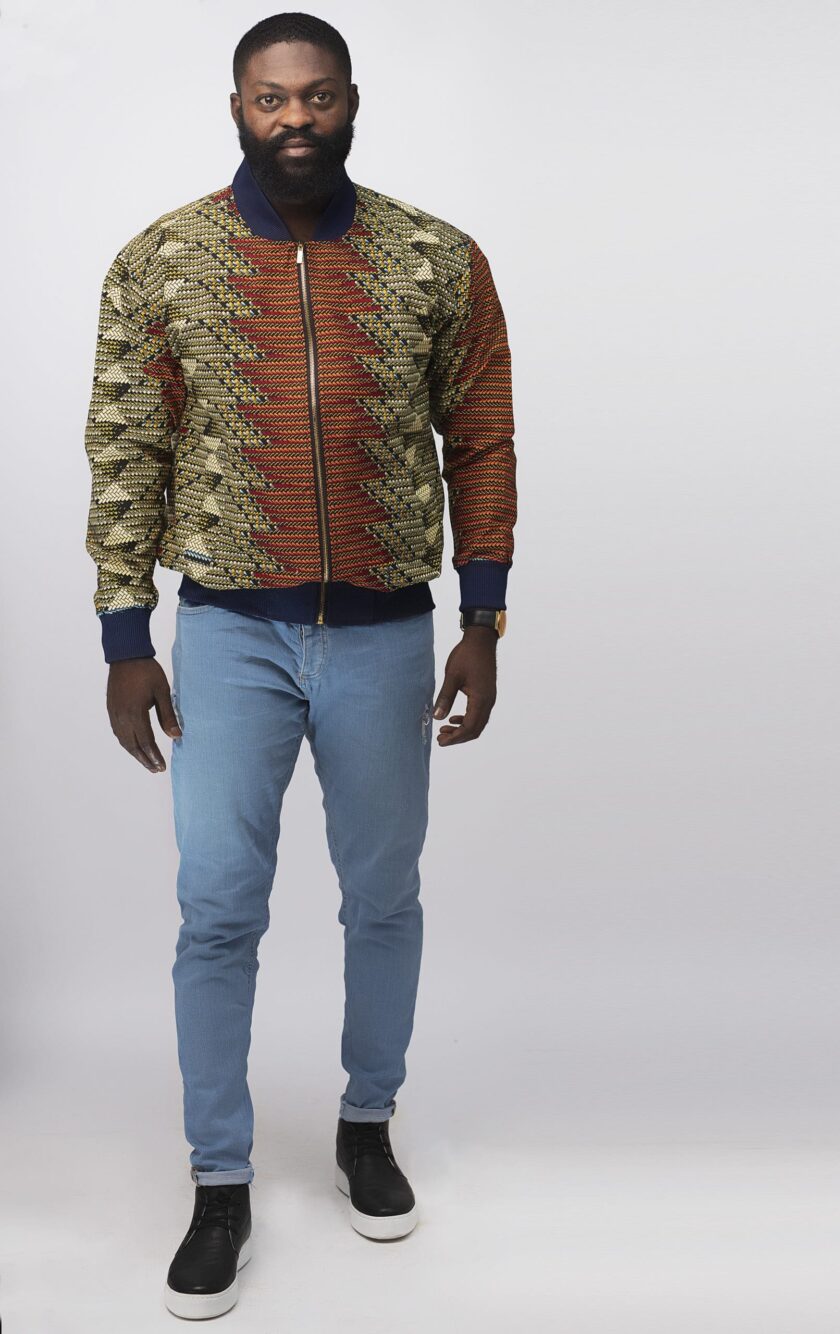 Frontal of model wearing our Abeba men's multi-coloured bomber jacket or baseball jacket in all over African print pattern.