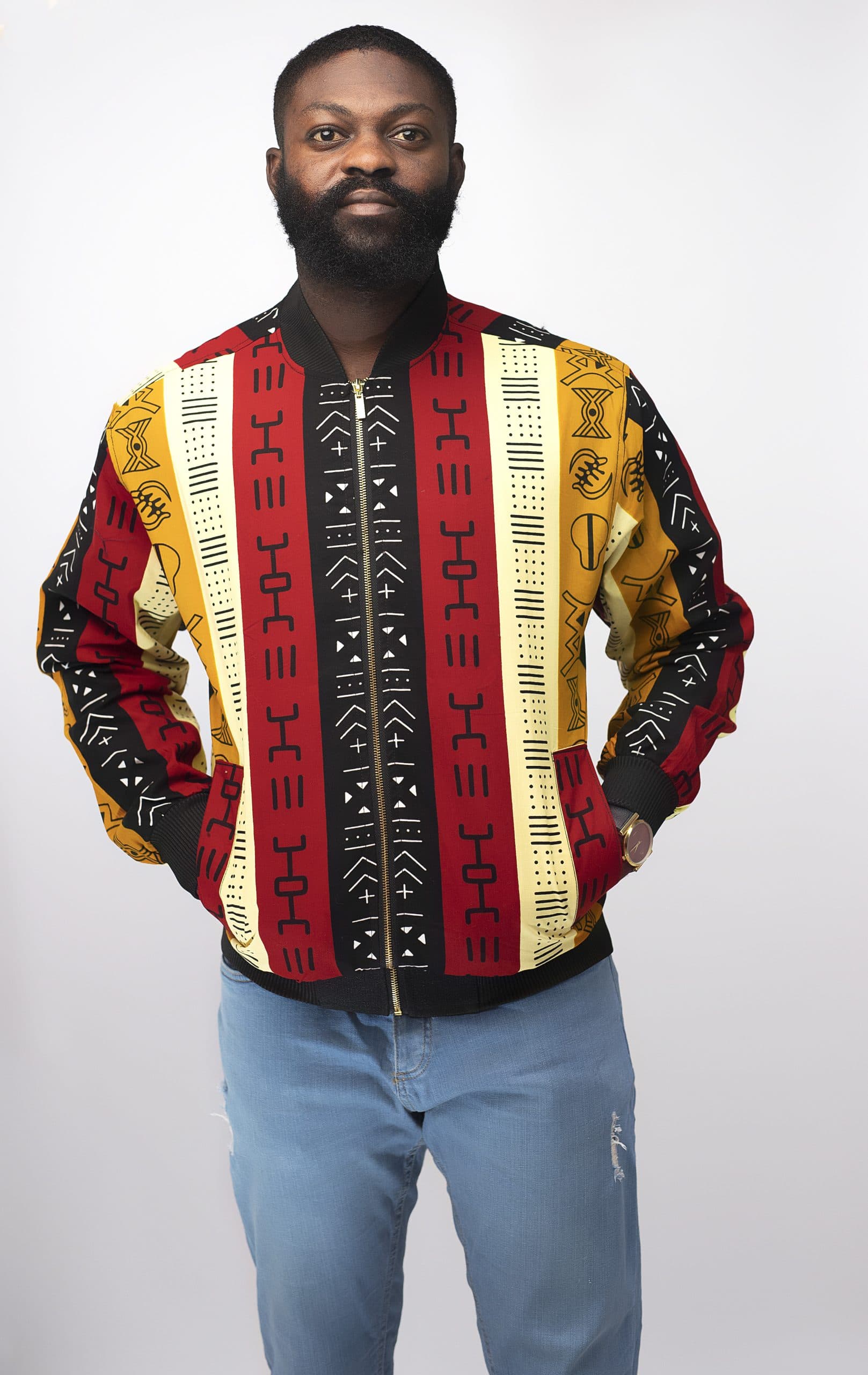 Frontal of model wearing our men's Kimani bomber jacket in all over colourful, striped, African Kente print pattern. Perfect for a festival!