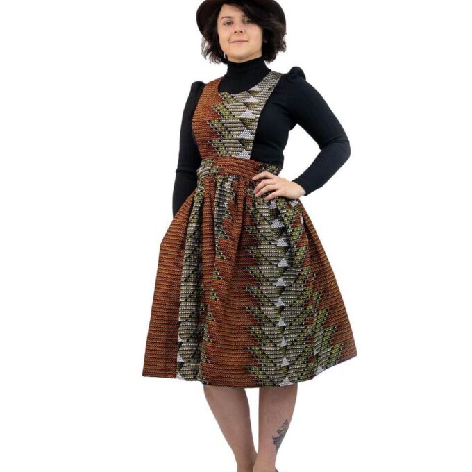 Full frontal of model wearing a pinafore skater dress in all over brown and grey geometric African print.