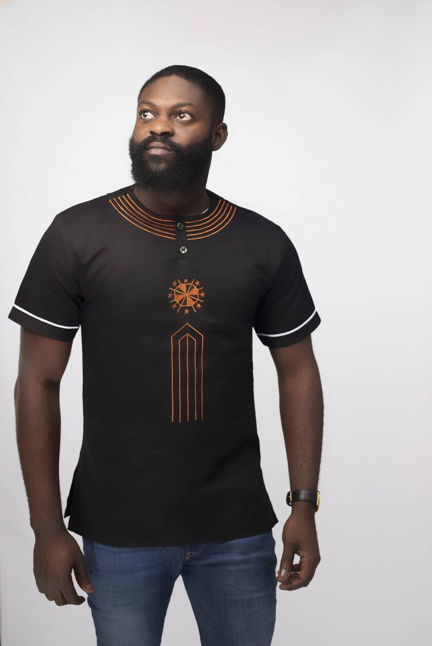 Close shot of model wearing our Mahbubi slim fit short sleeved black shirt with orange embroidery on the chest and neckline.