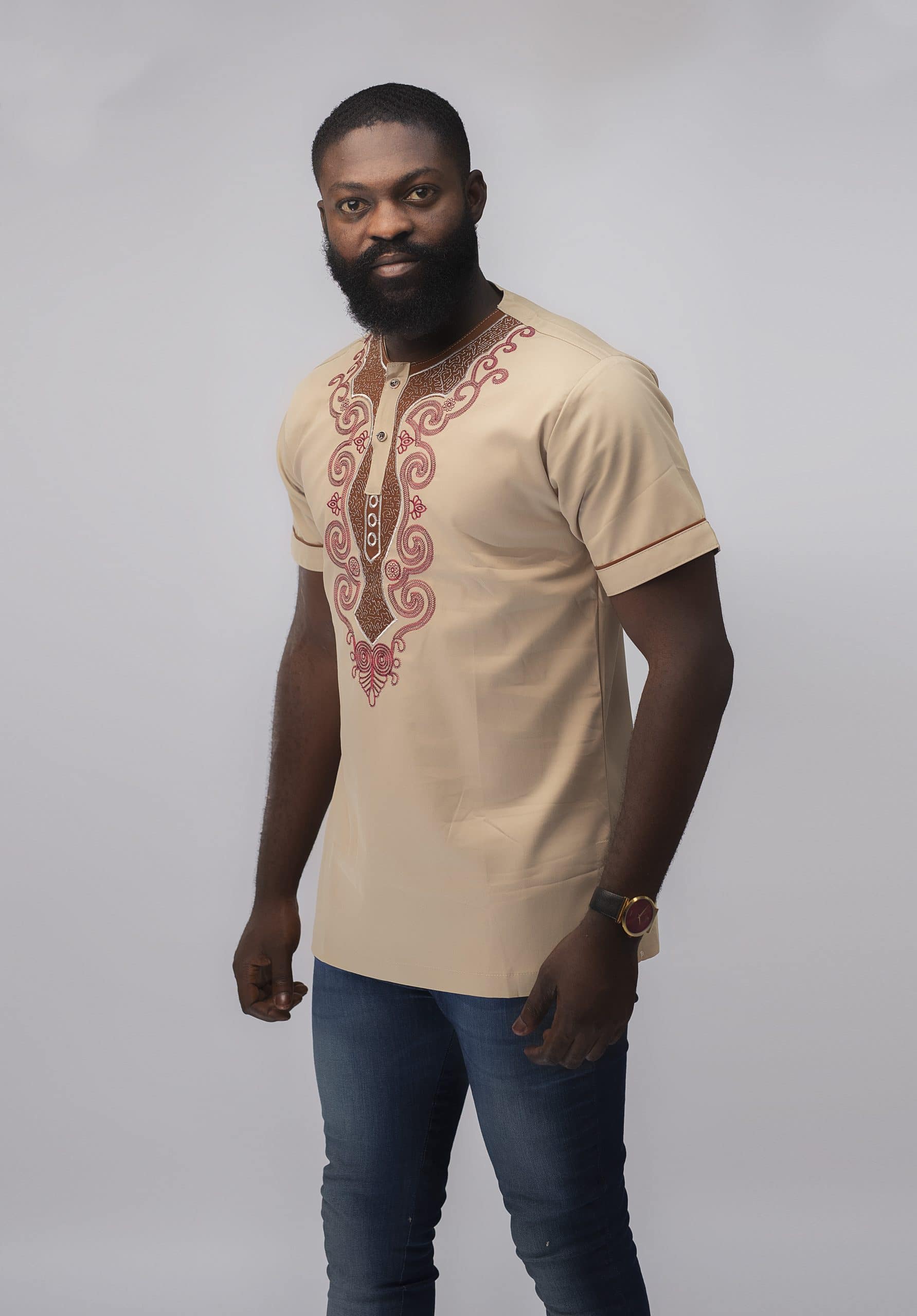 Frontal of model wearing our Melange Slim Fit Embroidered African Shirt in cream with elaborate red embroidery.
