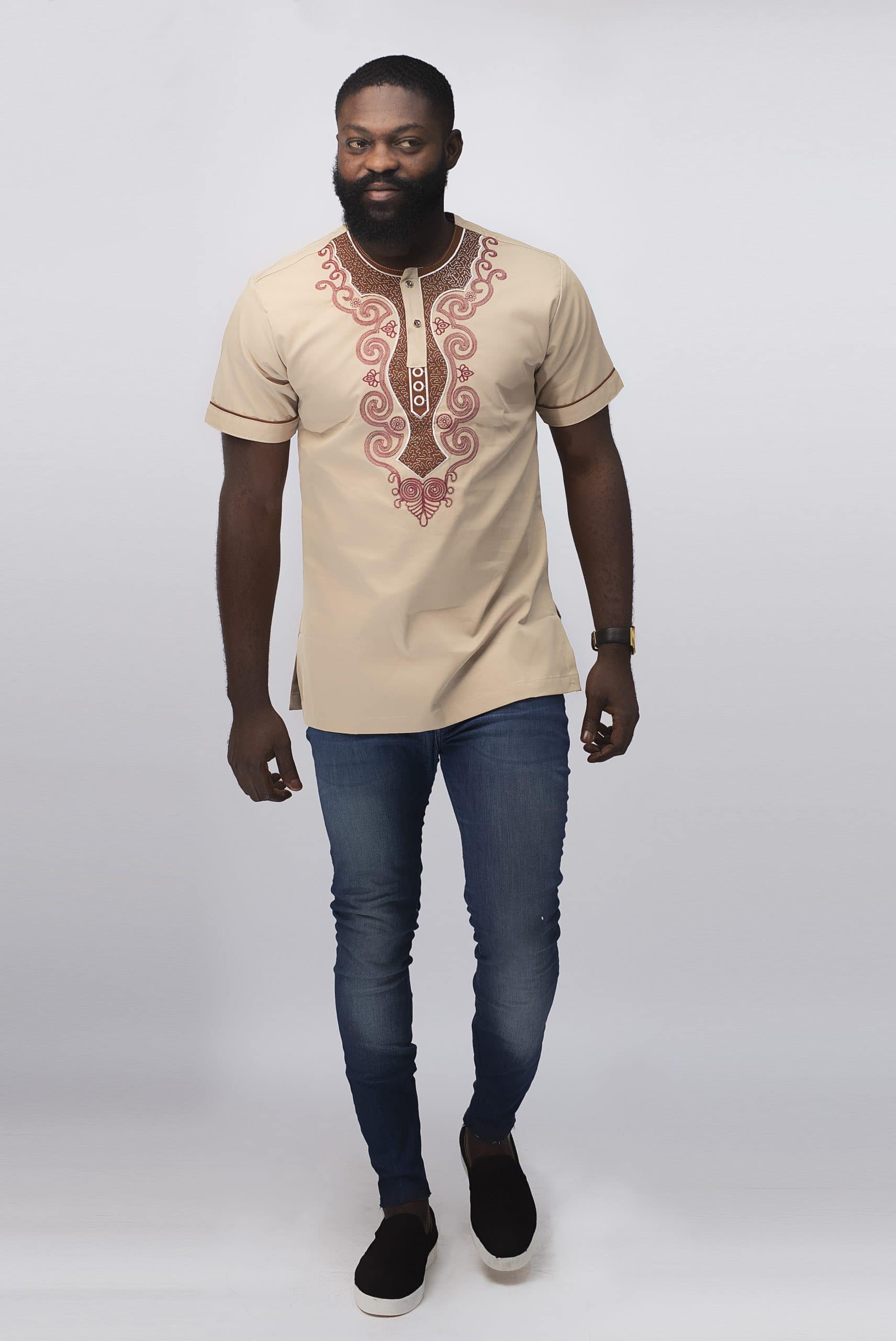 Frontal of model wearing our Melange Slim Fit Embroidered African Shirt in cream with elaborate red embroidery.