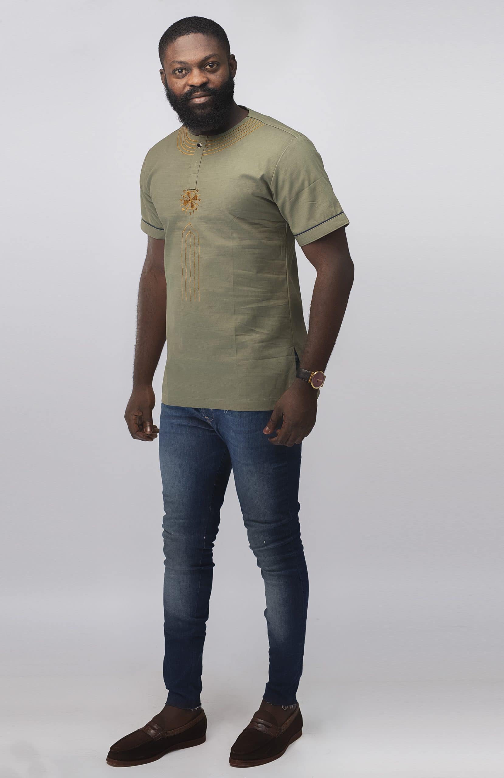 Close frontal of model wearing our Momar Slim Fit Embroidered African Shirt in khaki featuring a simple gold embroidery pattern on neckline, chest and black embroidery on the sleeves.