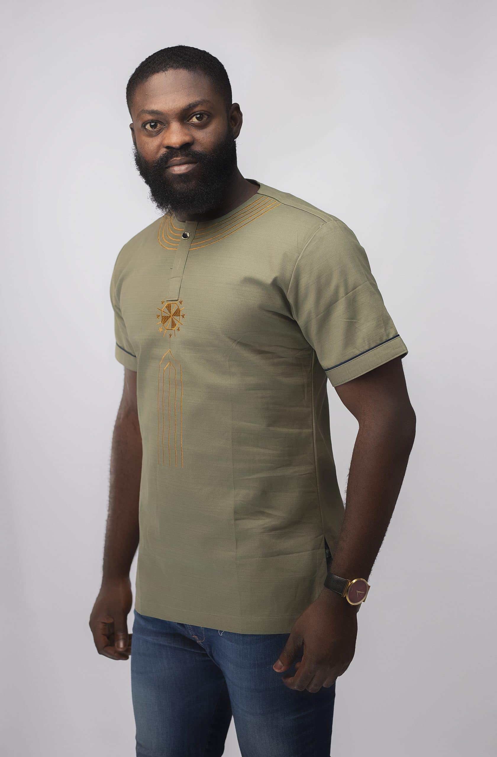 Frontal of model wearing our Momar Slim Fit Embroidered African Shirt in khaki featuring a simple gold embroidery pattern on neckline, chest and black embroidery on the sleeves.