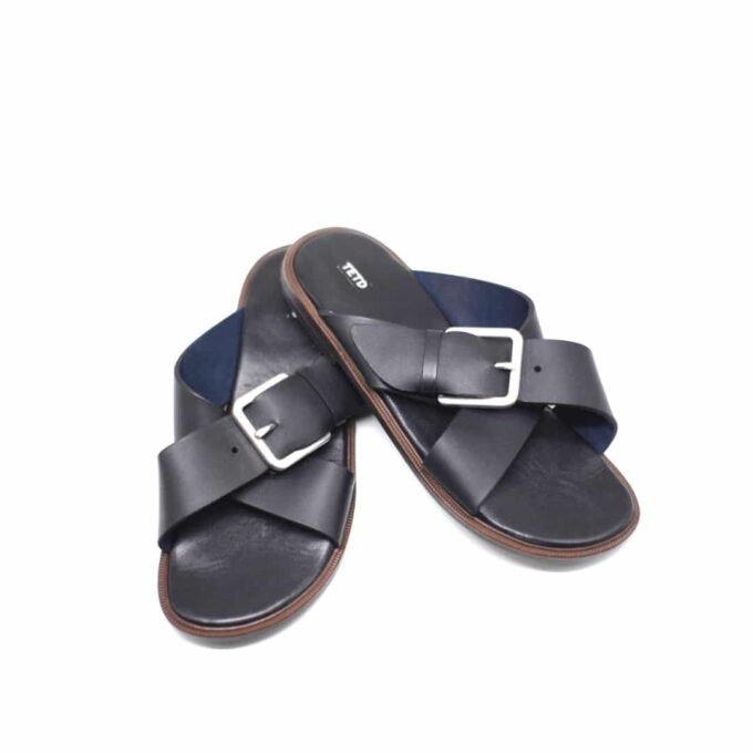 Shot of men's black leather sandals with cross strap design and buckle on one strap.