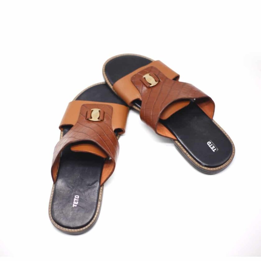 Shot of men's brown leather sandals with metal decor and crocodile pattern.