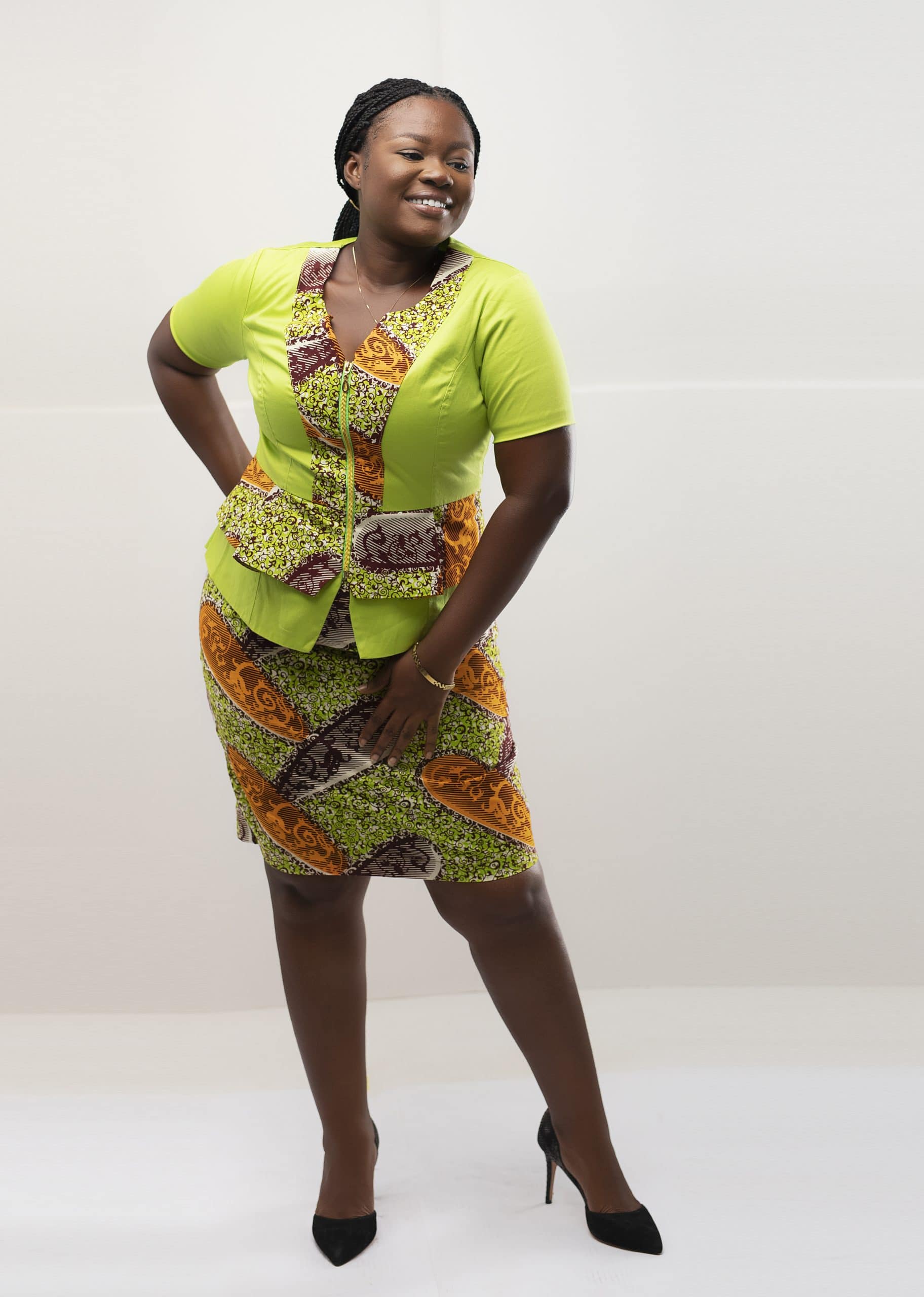 Frontal of model wearing our Ajua two piece peplum top and skirt set in contrasting lime green and gold and brown African print.