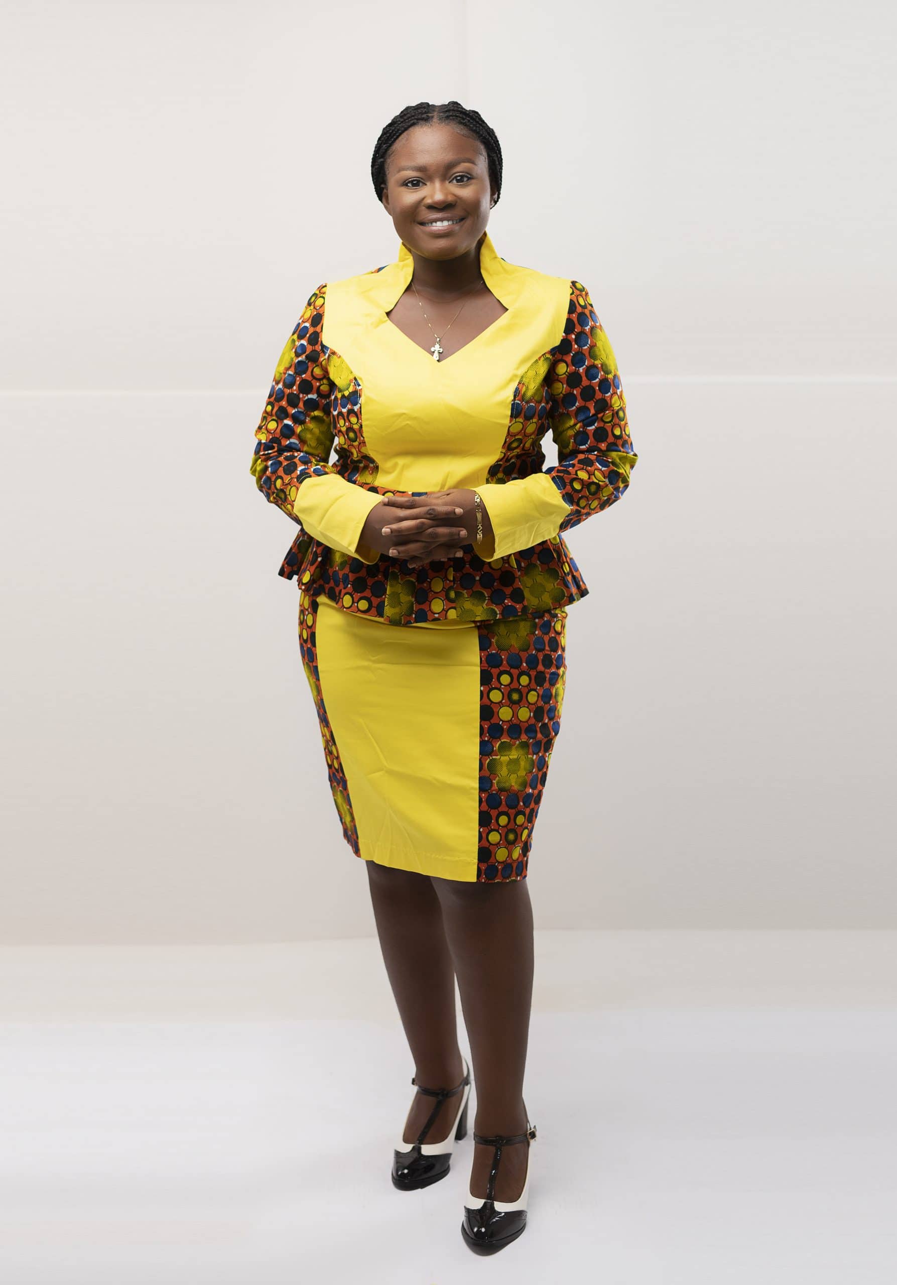 Frontal of model wearing our Zuri two piece matching skirt set in yellow, brown and blue African print. Features a statement collar and contrasting solid yellow panel on front and cuffs.