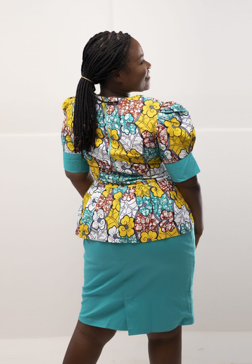 Back shot of model wearing our Ajo two-piece skirt set in light blue and yellow multi-coloured African floral print. Features a peplum top and contrasting matching skirt.