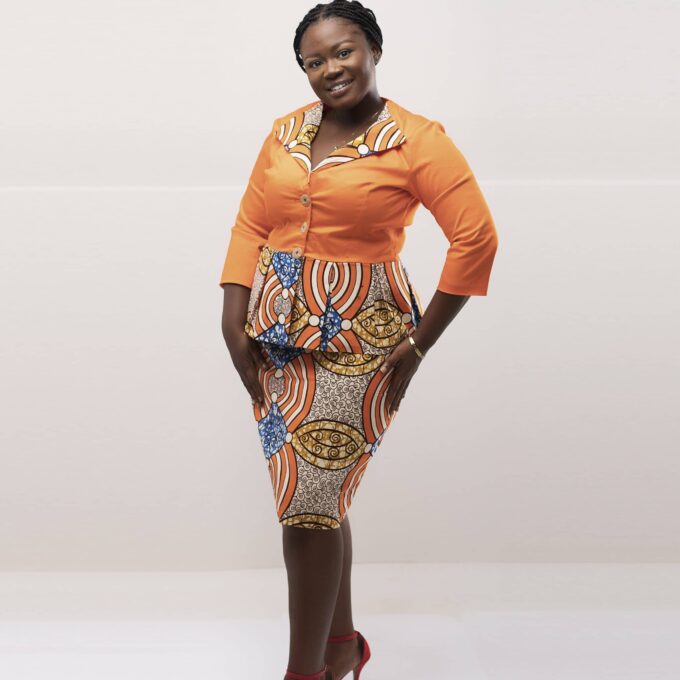 Frontal of model wearing our Amma two-piece skirt set in peach orange tones and multi-coloured African print. Features a peplum top and matching skirt.