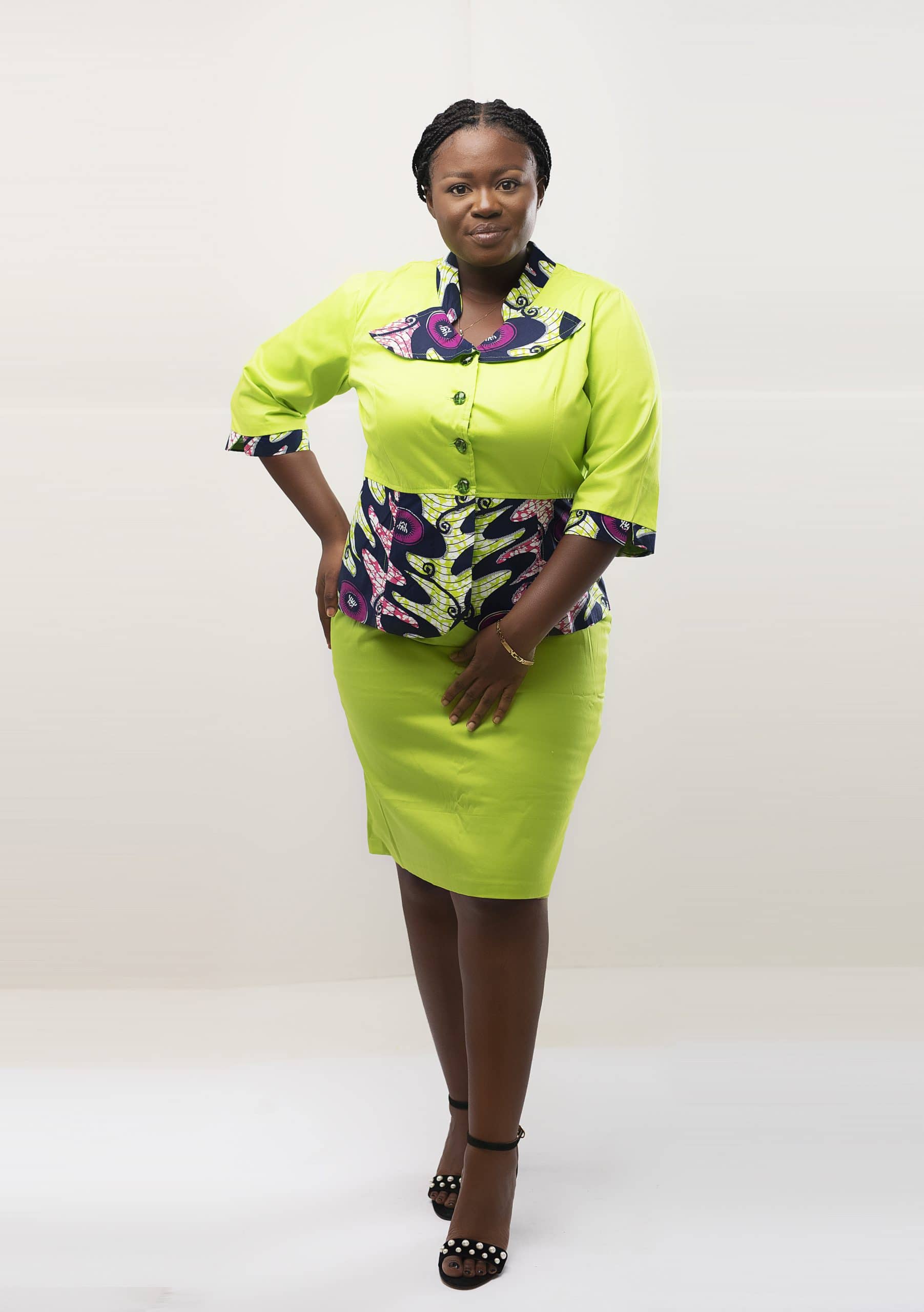 Frontal of model wearing our Afua two piece peplum top and skirt set in lime green and contrasting purple African print pattern. Features a solid lime green pencil skirt.