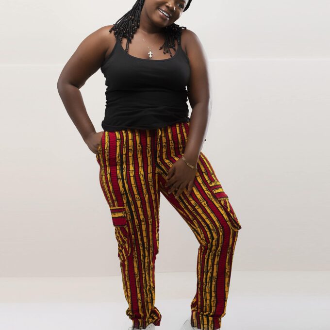 Frontal of model wearing our ladies Shani combat trousers or cargo pants in all over striped red and gold African print.