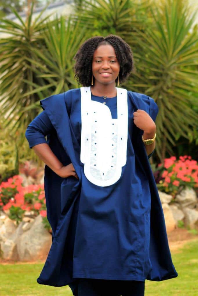 Frontal of model wearing a ladies traditional African three piece Agbada suit in navy blue with white embroidery detail on the front.