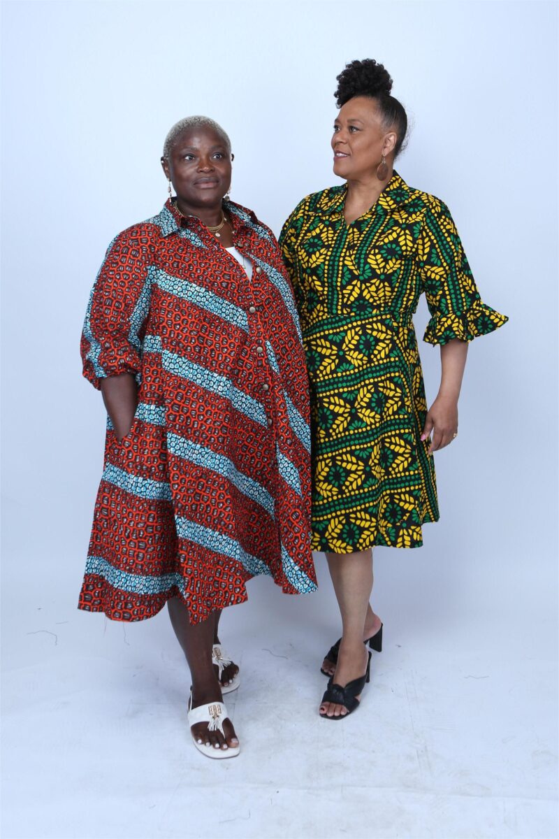 Woman wearing and orange and red striped African print shirt dress with another model standing beside.