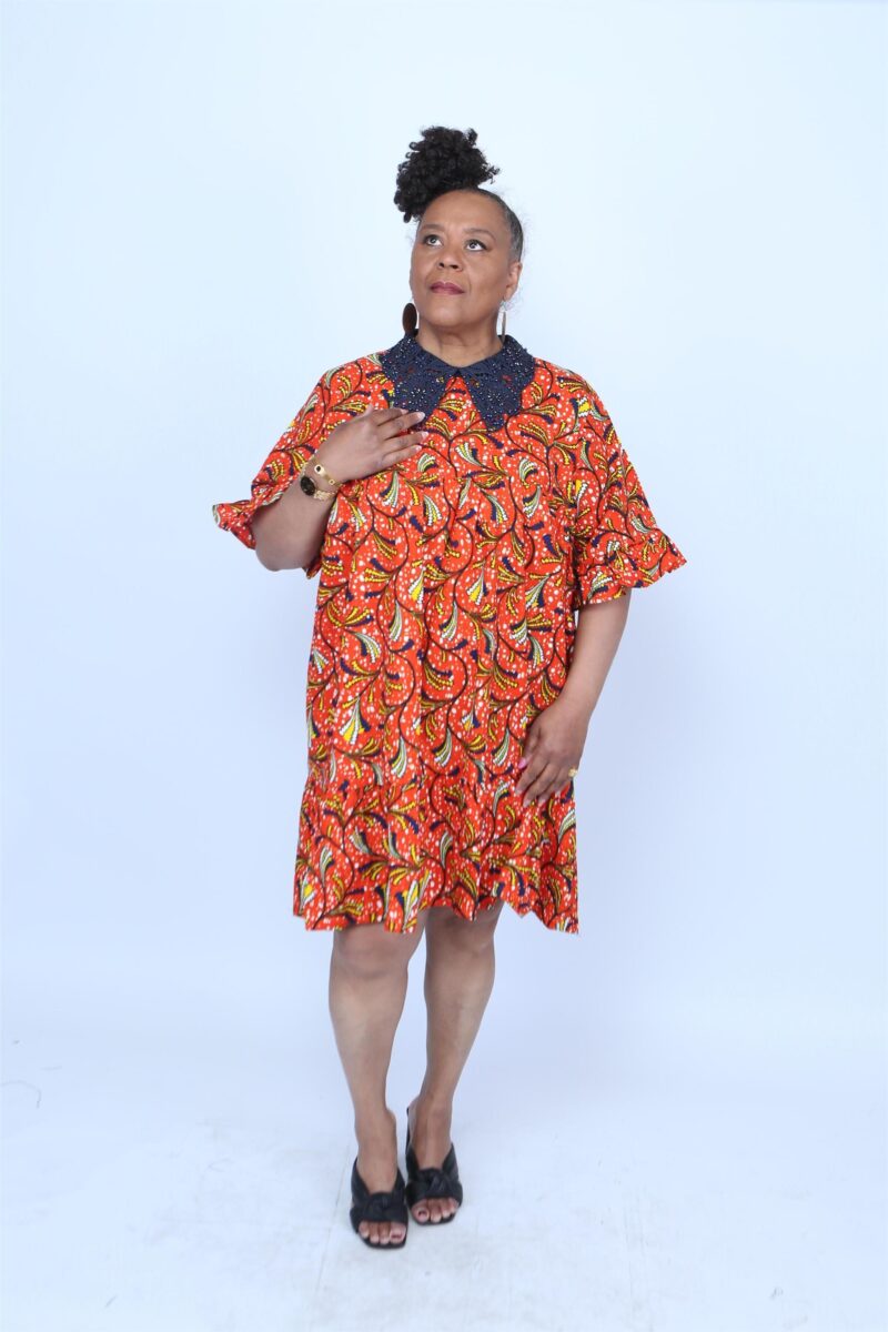 Woman posing while wearing a blue collar orange print african dress