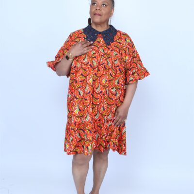 Woman posing while wearing an orange and blue african print dress
