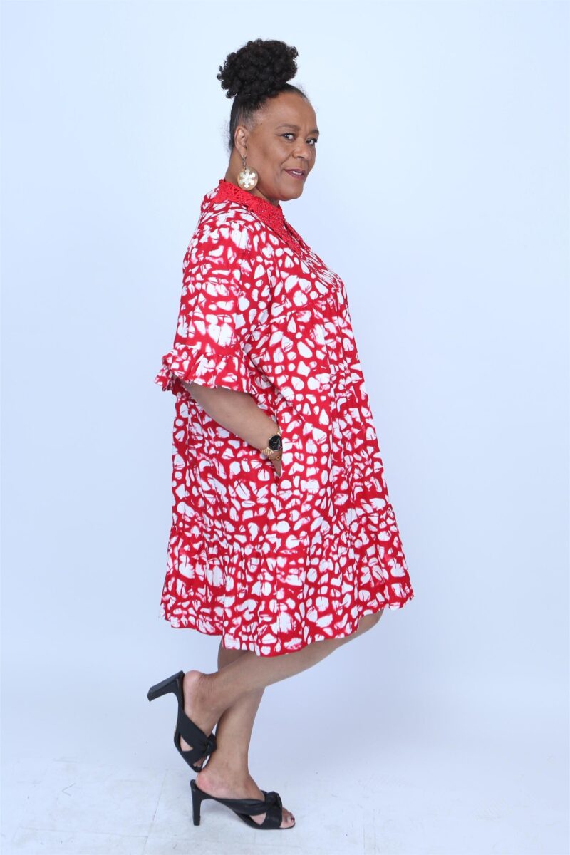 Woman standing to the side wearing a red and white african dress