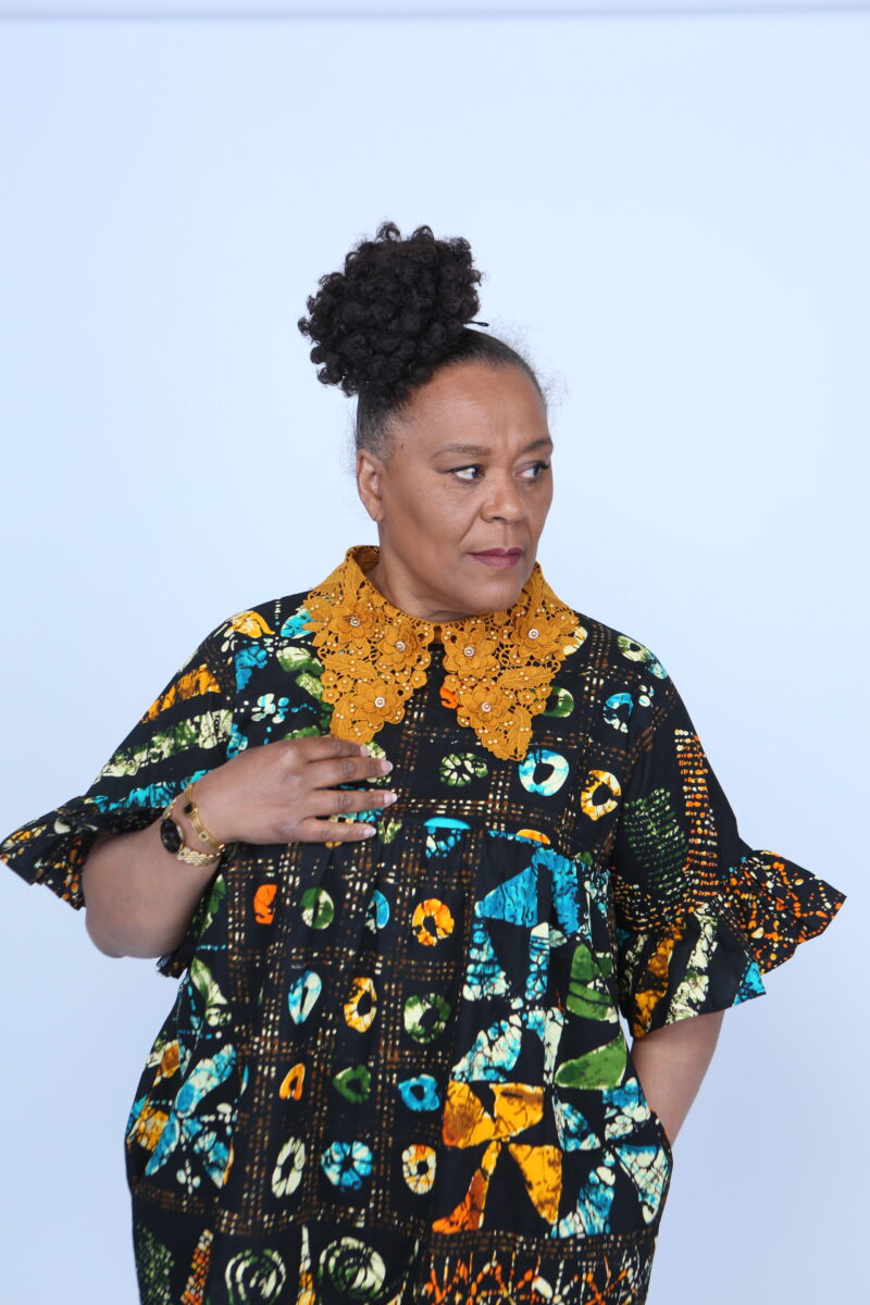 Woman wearing an african print dress with Gold collar.